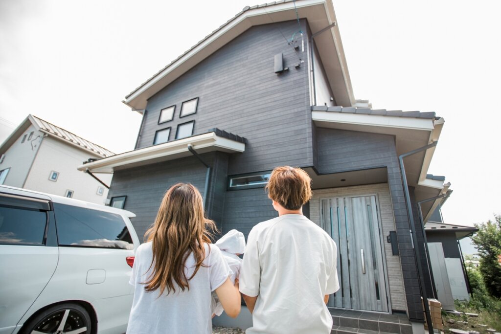 リフォームした住宅を見上げる夫婦のイメージ画像